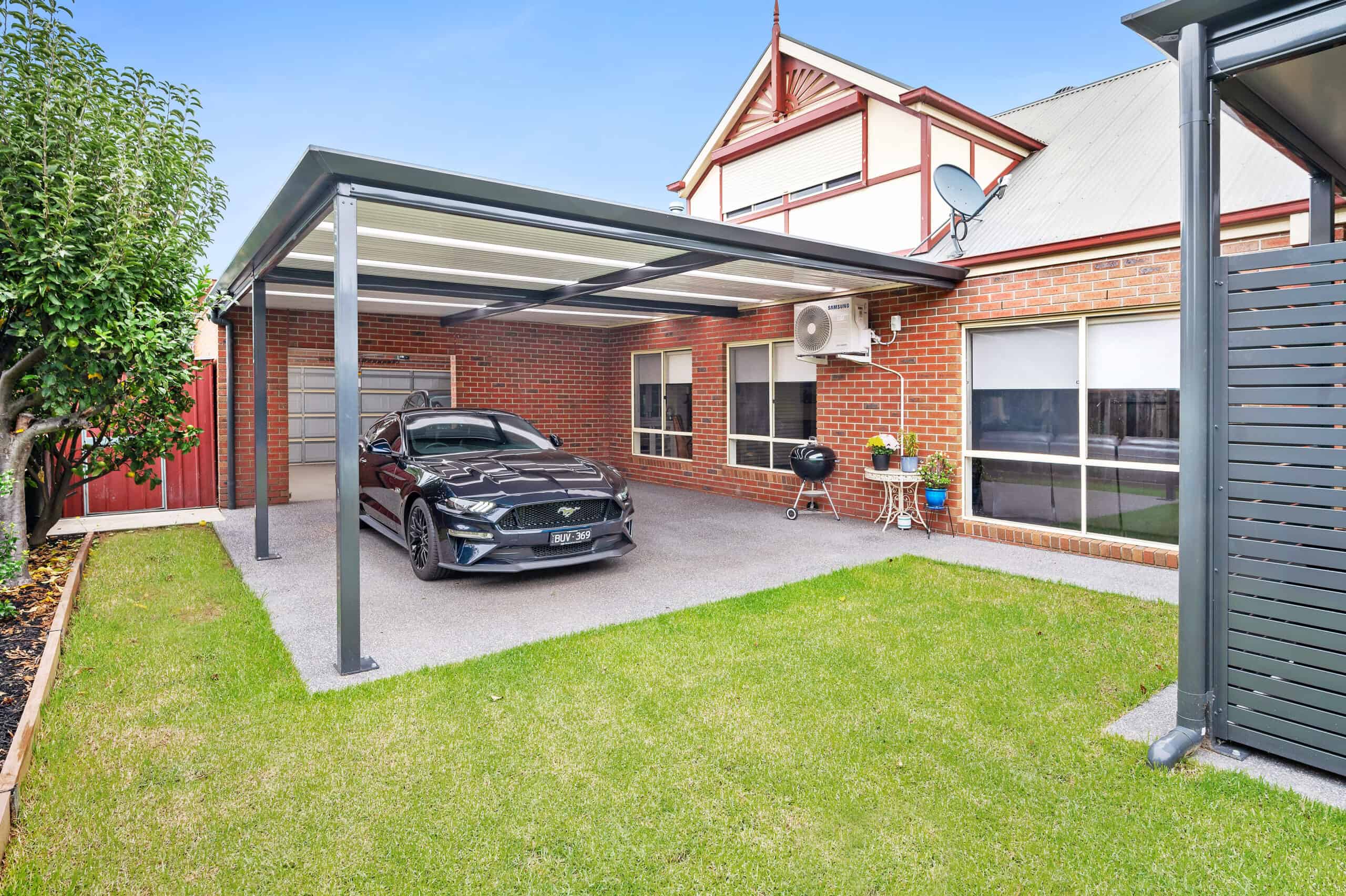 A Flat roof carport attached to a home with a vehicle parked under